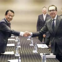 Finance Minister Taro Aso shakes hands with U.S. Treasury Secretary Steven Mnuchin before the two held talks on the sidelines of the Group of 20 meeting of finance ministers and central bank governors in the city of Fukuoka on Sunday. | KYODO