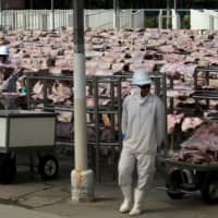 Workers carry salted meat that will be spreaded, dried and then packed at a plant of JBS S.A, the world\'s largest beef producer, in Santana de Parnaiba, Brazil, in 2017. | REUTERS