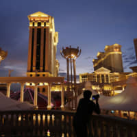 A man takes pictures of Caesars Palace hotel and casino, in Las Vegas in 2015. Eldorado Resorts will buy Caesars in a cash-and-stock deal valued at &#36;17.3 billion, creating a casino giant. The acquisition Monday puts about 60 casinos and resorts in 16 states under a single name, one of the biggest gambling and entertainment ventures in the United States. | AP