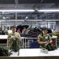 Workers conduct quality checks on products at a factory owned by Yakeda Outdoor Travel Products Co. in Yangon on June 11. | REUTERS
