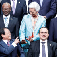 Finance Minister Taro Aso and International Monetary Fund Managing Director Christine Lagarde gesture as they pose for a photo at the Group of 20 meeting of finance ministers and central bank governors in the city of Fukuoka on Sunday. | REUTERS