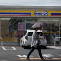 A pedestrian walks past a convenience store, operated by Ministop Co., in Sakura, Chiba Prefecture, in October 2016. | BLOOMBERG