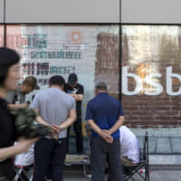 People play checkers outside a Baoshang Bank Co. branch in Beijing May 28. A Bloomberg index of Hong Kong-listed Chinese banks is set for its biggest monthly loss this year after regulators assumed control of Baoshang on Friday citing \"serious\" credit risks. | BLOOMBERG