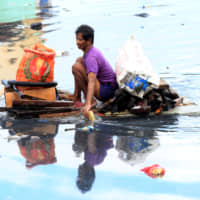 A man uses an improvised banca to collect plastic materials in a polluted river in Manila in 2016. | REUTERS