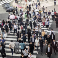 Pedestrians cross a road in the Ginza shopping district of Tokyo in May of last year. | BLOOMBERG