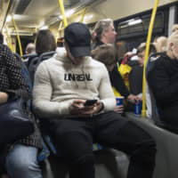 Passengers look at their smartphones as they ride a bus in Moscow on May 16. Russia\'s communications regulator says that Tinder is now required to provide user data to Russian intelligence agencies. | AP