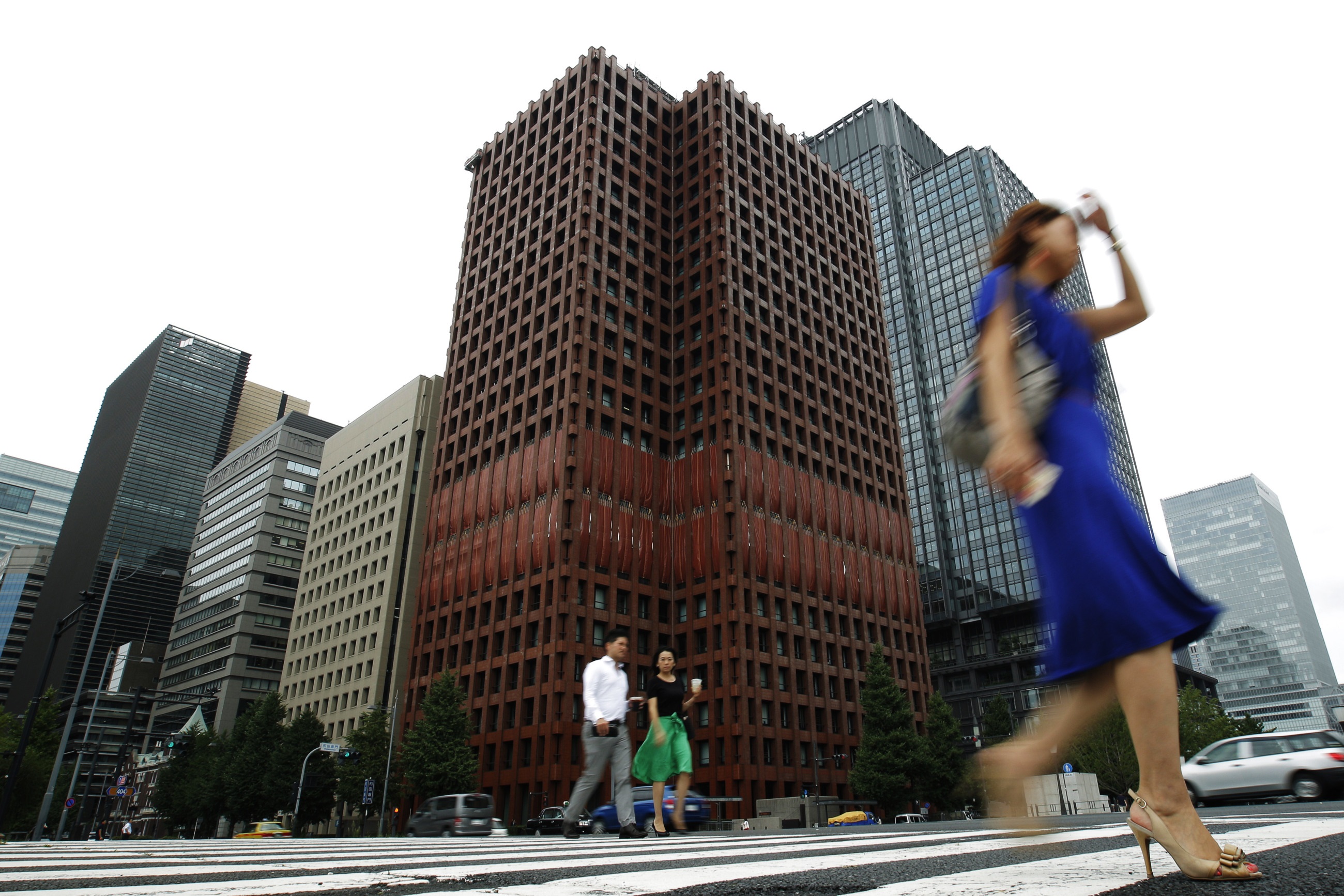 Pedestrians cross a road in front of Tokio Marine Holdings Inc. headquarters in Tokyo.  | KYODO
