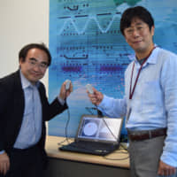 Miraisens Inc. CEO Natsuo Koda (right) and founder and Chief Technology Officer Norio Nakamura hold a palm-sized device equipped with 3D Haptics, which can recreate a variety of touch sensations in a three-dimensional space. | MASUMI KOIZUMI