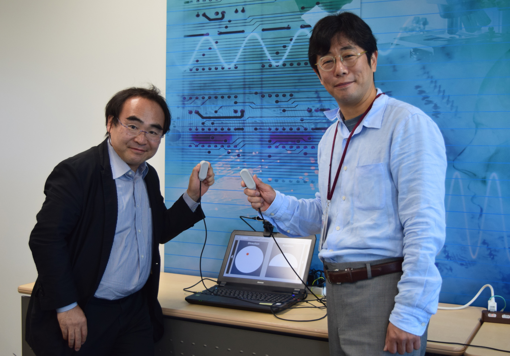 Miraisens Inc. CEO Natsuo Koda (right) and founder and Chief Technology Officer Norio Nakamura hold a palm-sized device equipped with 3D Haptics, which can recreate a variety of touch sensations in a three-dimensional space. | MASUMI KOIZUMI