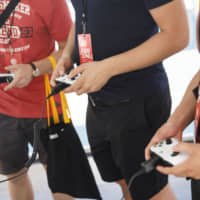 Attendees hold Microsoft Corp. Xbox One controllers while playing during a UbiSoft Entertainment SA event ahead of the E3 Electronic Entertainment Expo in Los Angeles on Monday. Ubisoft announced that Uplay+, its new subscription service, will launch on Sept. 3 for Windows PC. Players will be able to download more than 100 games, including new releases. Photographer: Patrick T. Fallon/Bloomberg | BLOOMBERG