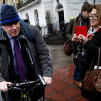 Then-London Mayor Boris Johnson cycles off after speaking to the media in front of his home in February 2016. | REUTERS
