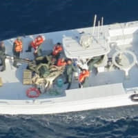 A U.S. military image released by the Pentagon in Washington on Monday shows what the Pentagon says are members of the Islamic Revolutionary Guard Corps Navy photographed from a U.S. Navy MH-60R helicopter after removing an unexploded limpet mine from the M/T Kokuka Courageous, a Japanese owned commercial tanker, after it was attacked with another mine that did explode on June 13. | U.S. NAVY / HANDOUT / VIA REUTERS