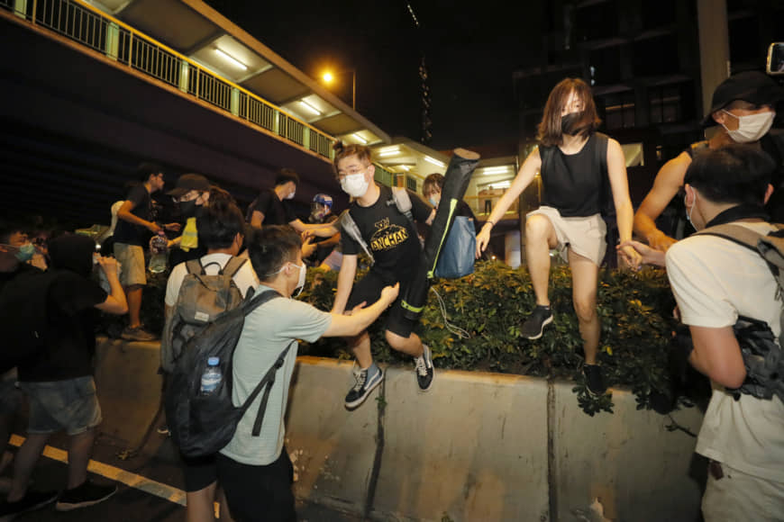 Protesters climb over a barrier near the Legislative Council in Hong Kong during the early hours of Monday. | AP
