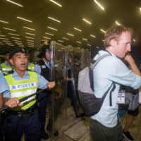 Police in riot gear direct journalists outside the Legislative Council in Hong Kong on Monday. | BLOOMBERG