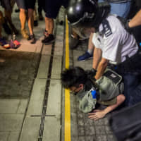 Police detain a demonstrator outside Hong Kong\'s Legislative Council during a protest against a proposed extradition law early on Monday. | BLOOMBERG