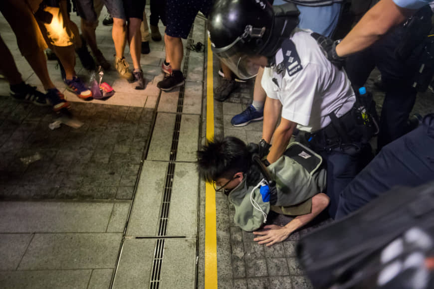 Police detain a demonstrator outside Hong Kong's Legislative Council during a protest against a proposed extradition law early on Monday. | BLOOMBERG