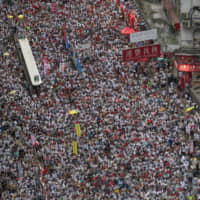 Demonstrators march during a protest against a proposed extradition law in Hong Kong on Sunday. An estimated 1 million people turned out to oppose the measure. | BLOOMBERG