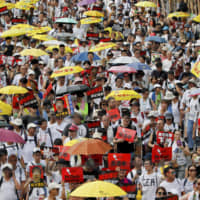 Protesters holding umbrellas and placards march as they take part in a rally against the proposed extradition law in Hong Kong on Sunday | AP