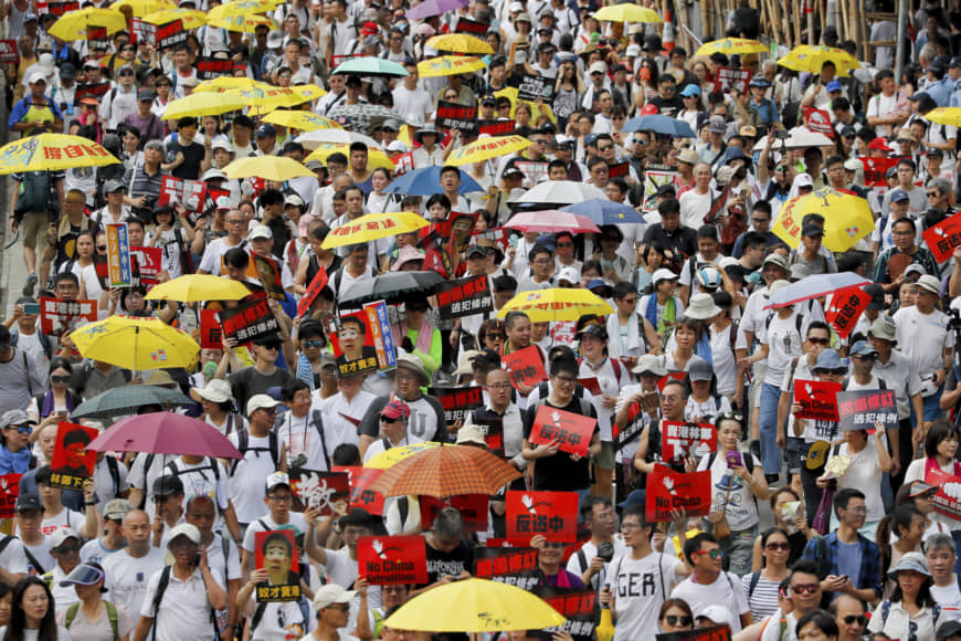 Protesters holding umbrellas and placards march as they take part in a rally against the proposed extradition law in Hong Kong on Sunday | AP