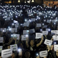 Hundreds of mothers holding placards, some of which read \"If we lose the young generation, what\'s left of Hong Kong,\" and lit smartphones protest against the amendments to the extradition law in Hong Kong on Friday night. | AP