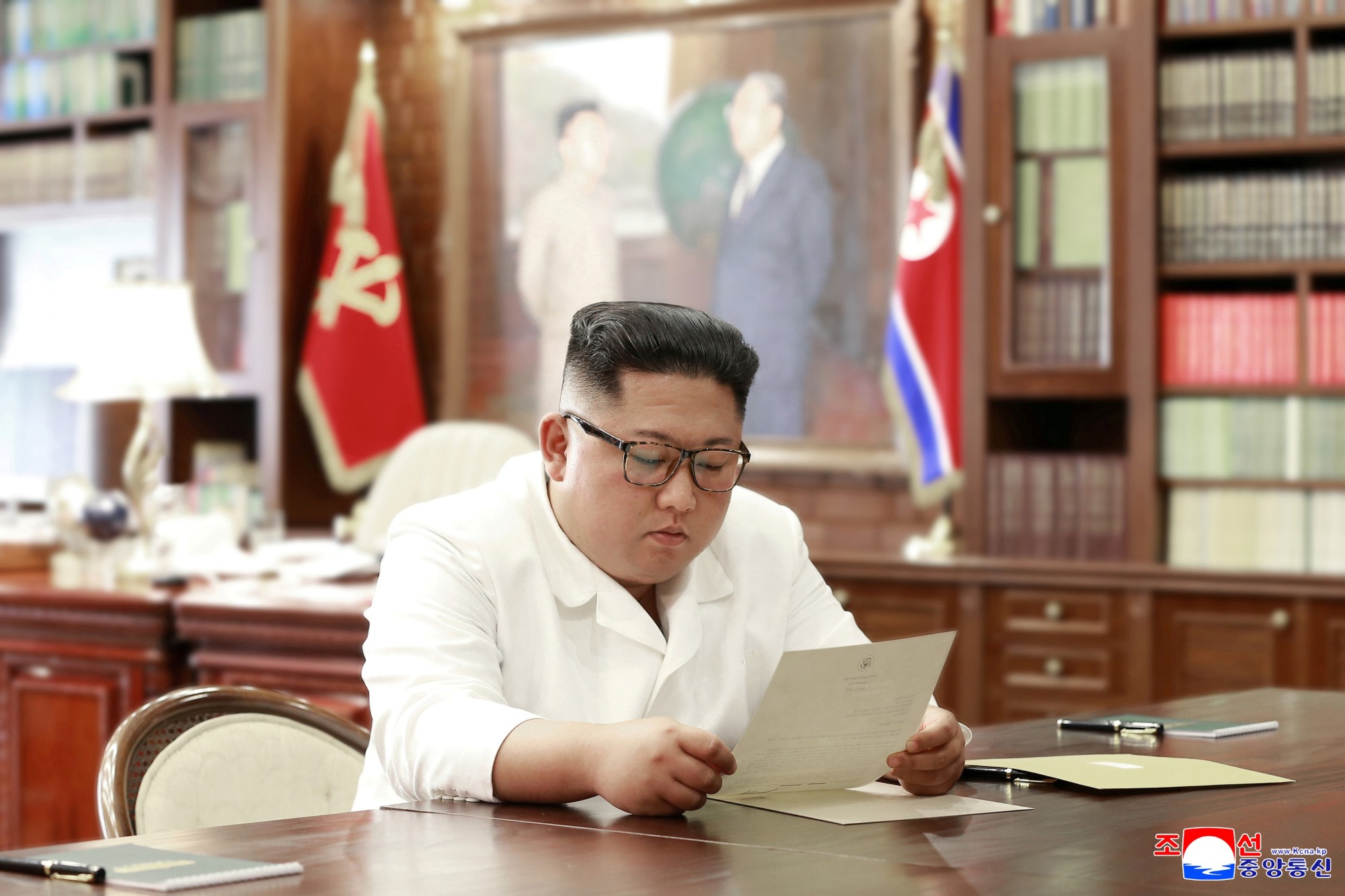 North Korean leader Kim Jong Un reads a letter from U.S. President Donald Trump in Pyongyang in this picture released Sunday. | REUTERS