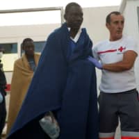 A migrant, rescued by the ferry Vronskiy off the Spanish coast in the Mediterranean Sea, walks as he is helped by Red Cross members after arriving at the port of Motril, southern Spain, Wednesday. | REUTERS