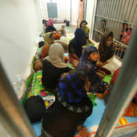 Rohingya are seen detained in a police station after a fishing boat carrying more than 60 Rohingya refugees was found beached at Rawi island, part of Tarutao national park in the province of Satun, Thailand, bordering with Malaysia, Wednesday. | REUTERS