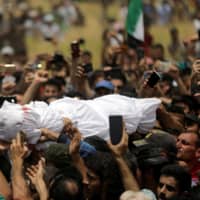People use their mobile phones to take pictures of the body of Abdelbasset al-Sarout, 27, who died from wounds he sustained battling in northwest Syria, during his funeral in the border town of al-Dana, Idlib, Syria, Sunday. | REUTERS