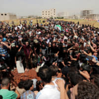 People gesture and chant slogans during the funeral of Abdelbasset al-Sarout, 27, who died from wounds he sustained battling in northwest Syria, in the border town of al-Dana, Idlib, Syria, Sunday. | REUTERS