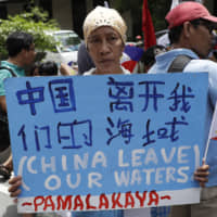 A protester holds a sign during a rally outside the Chinese Consulate in the financial district of Makati, in Metropolitan Manila, during an event marking Independence Day on Wednesday. | AP