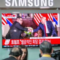People watch a television broadcast in Seoul featuring images of U.S. President Donald Trump and North Korean leader Kim Jong Un during their summit in Singapore on June 12, 2018. | BLOOMBERG