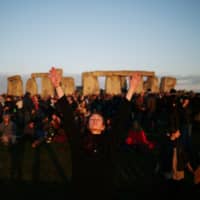 Revelers welcome the summer solstice sunrise at Stonehenge in Amesbury, England, on Friday. | REUTERS