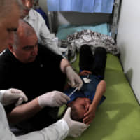 Doctors treat a wounded Syrian refugee girl at a mobile clinic in north Azaz, Syria, June 13. | REUTERS