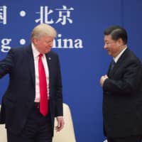 U.S. President Donald Trump gestures next to Chinese leader Xi Jinping during a business leaders event at the Great Hall of the People in Beijing in November 2017. | AFP-JIJI