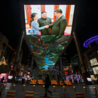 Footage showing Chinese President Xi Jinping and North Korean leader Kim Jong Un is seen on a television at a shopping mall in Beijing on Jan. 10. | REUTERS
