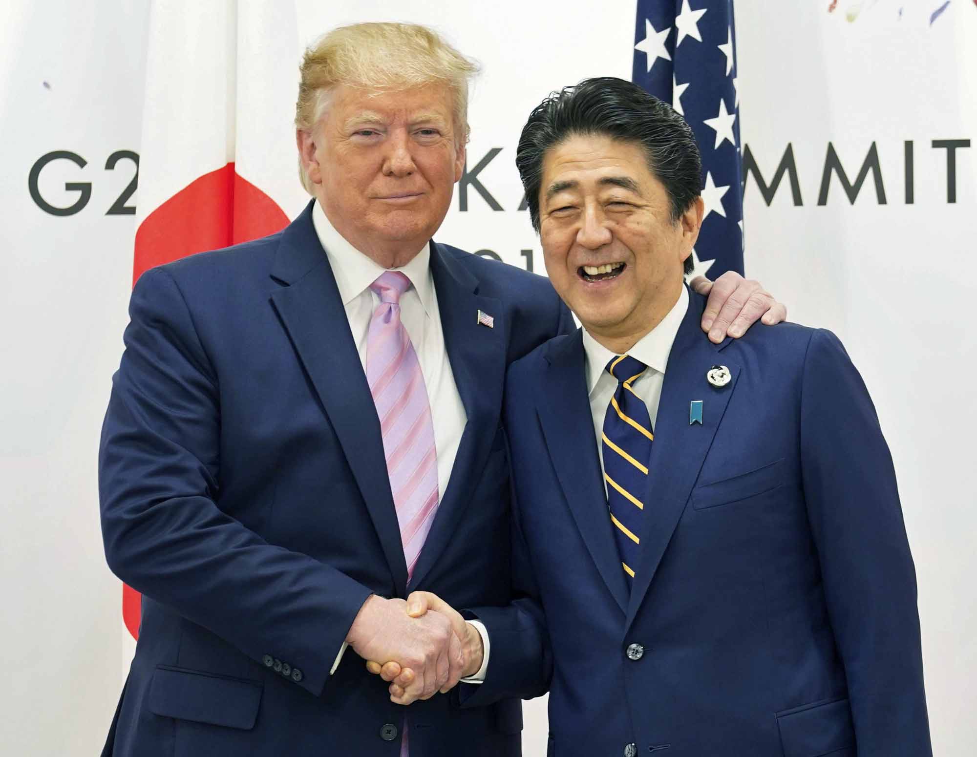U.S. President Donald Trump shakes hands with Prime Minister Shinzo Abe during the Group of 20 leaders summit in Osaka on Friday. | REUTERS / VIA KYODO