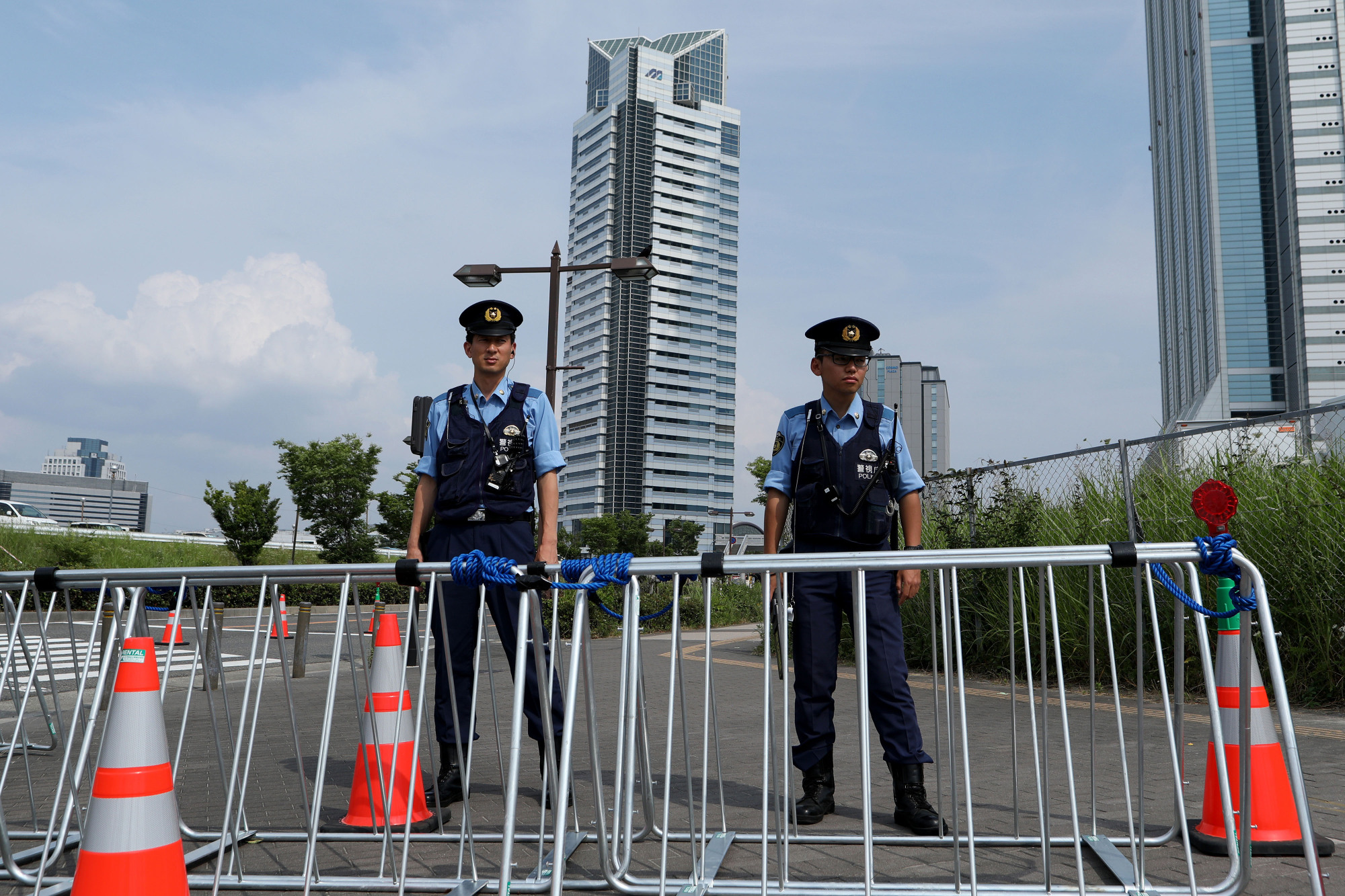 Police officers stand guard behind barricades Saturday near the Intex Osaka convention center as preparations continue for the Group of 20 Summit. | BLOOMBERG
