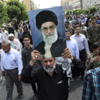 A demonstrator holds up a poster of Iranian Supreme Leader Ayatollah Ali Khamenei in Tehran on Friday during the annual Quds, or Jerusalem Day, rally. | AP