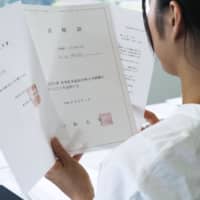 A woman who wasn\'t accepted into Juntendo University\'s medical school looks at a letter of apology from the school last month. The letter said the exam was manipulated to accept less women and she actually got passing scores. | KYODO