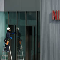 A worker cleans a window at Nissan\'s headquarters in Yokohama last November. | BLOOMBERG