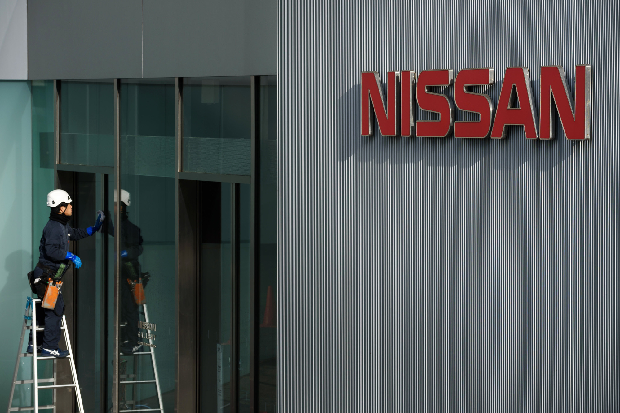 A worker cleans a window at Nissan's headquarters in Yokohama last November. | BLOOMBERG
