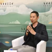 Studio Ponoc CEO Yoshiaki Nishimura speaks at a news conference in Annecy, France, on Monday as Francis Gabet, director of the Olympic Foundation for Culture and Heritage, looks on. | KYODO