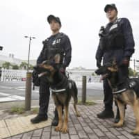 Officers with police dogs patrol around the venue of the Group of 20 summit in Osaka on Thursday, a day before the meeting begins. | KYODO