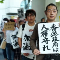 Protesters hold up a placard reading \"Hong Kong Government, Protect Human Rights\" on Thursday in Tokyo during a rally in front of the Hong Kong Economic and Trade Office in Chiyoda Ward.  About 300 people gathered to show support for demonstrators in Hong Kong protesting against a controversial extradition bill. | RYUSEI TAKAHASHI