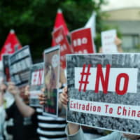 Protesters hold up placards in front of the Hong Kong Economic and Trade Office in Tokyo\'s Chiyoda Ward on Thursday to show support for demonstrators in Hong Kong protesting a controversial extradition bill. About 300 people joined the demonstration. | RYUSEI TAKAHASHI