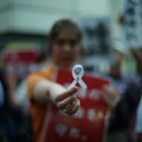 Mandy Tang, a 19-year-old exchange student from Hong Kong, shows a white ribbon during a protest rally in Tokyo on Thursday. The ribbon symbolizes support for those protesting in Hong Kong against a controversial extradition bill. She spent the night before the protest folding nearly a hundred ribbons. | RYUSEI TAKAHASHI