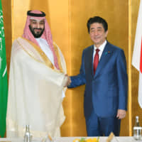 Prime Minister Shinzo Abe and Saudi Arabian Crown Prince Mohammed bin Salman shake hands ahead of their talks in Osaka on Sunday. | KYODO