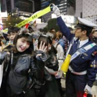 People in costumes celebrate Halloween on Shibuya crossing on Oct. 31 as a police officer tries to help control the crowd. | KYODO