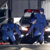 Police investigate the scene where two men were stabbed late Monday in Nagoya. | KYODO