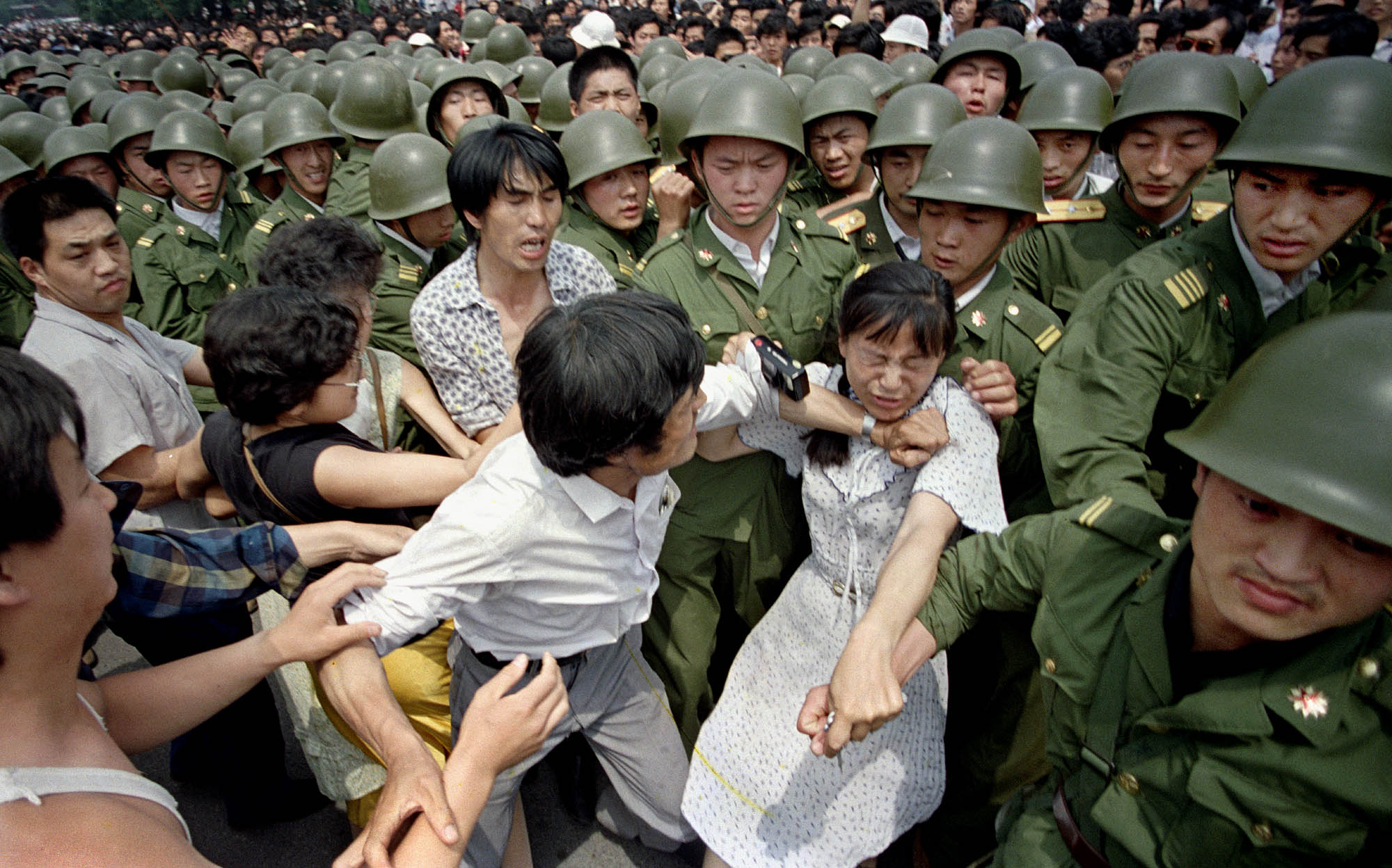 A young woman is caught between civilians and Chinese soldiers who were trying to remove her from an assembly near the Great Hall of the People in Beijing, on June 3, 1989.  | AP